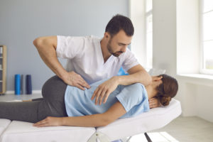 Chiropractic Adjustments - What’s Cracking? - Man doctor chiropractor or osteopath fixing lying womans back in manual therapy clinic